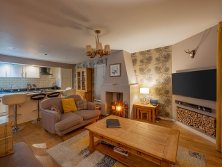 Courtyard Cottage 11 The living room and kitchen and a wood burning stove in Courtyard Cottage 11 at Abbey Holidays Loch Ness