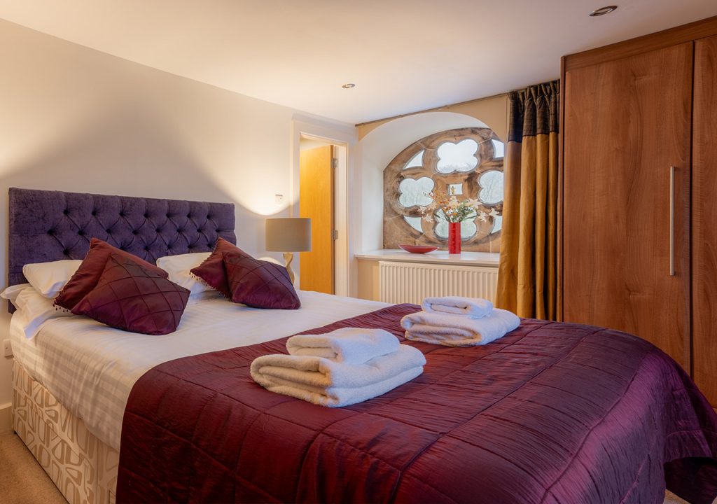 A double bedroom with a stunning stone church window in Moat House 5 at Abbey Holidays Loch Ness