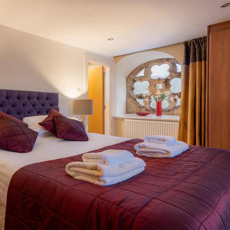 A double bedroom with a stunning stone church window in Moat House 5 at Abbey Holidays Loch Ness