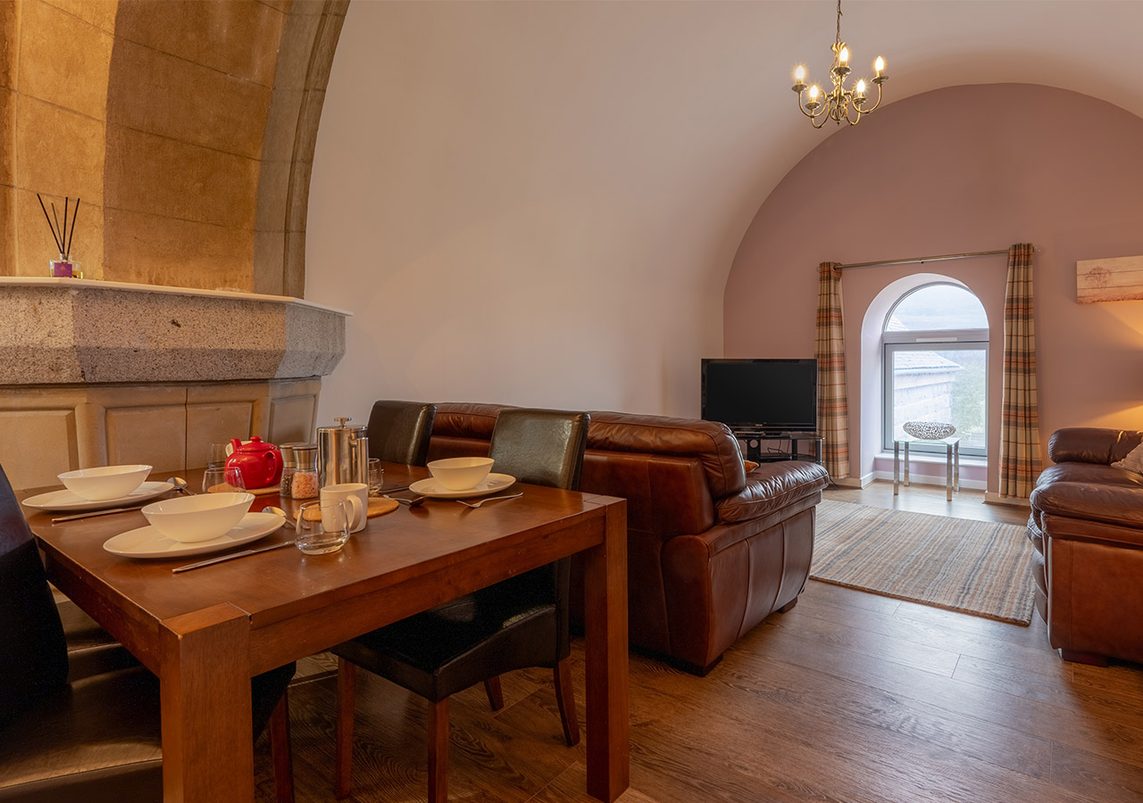 A luxurious dining area and living room with a stone archway in the Glen Affric accommodation at Abbey Holidays Loch Ness