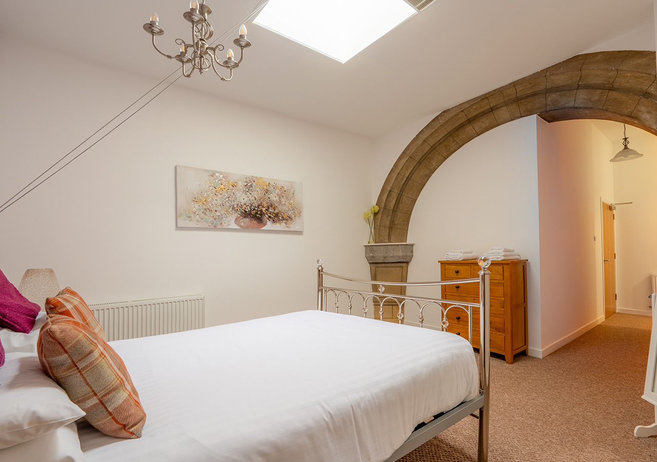 A luxurious bedroom with a stone archway in the Glen Affric accommodation at Abbey Holidays Loch Ness