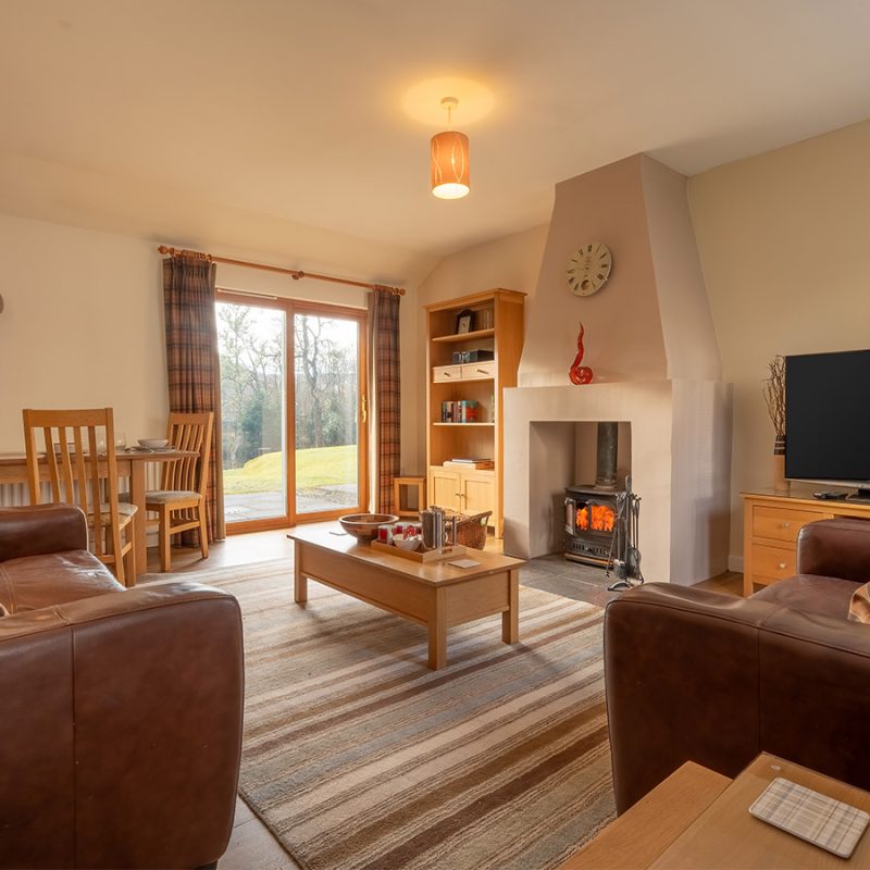 The living room with cosy fireplace in the Club Cottage accommodation at Abbey Holidays Loch Ness