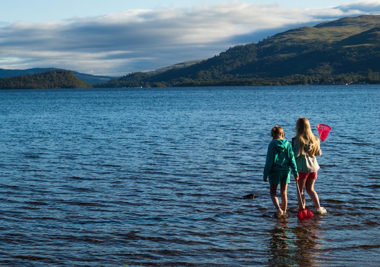 Two kids paddling in Loch Ness in Autumn.