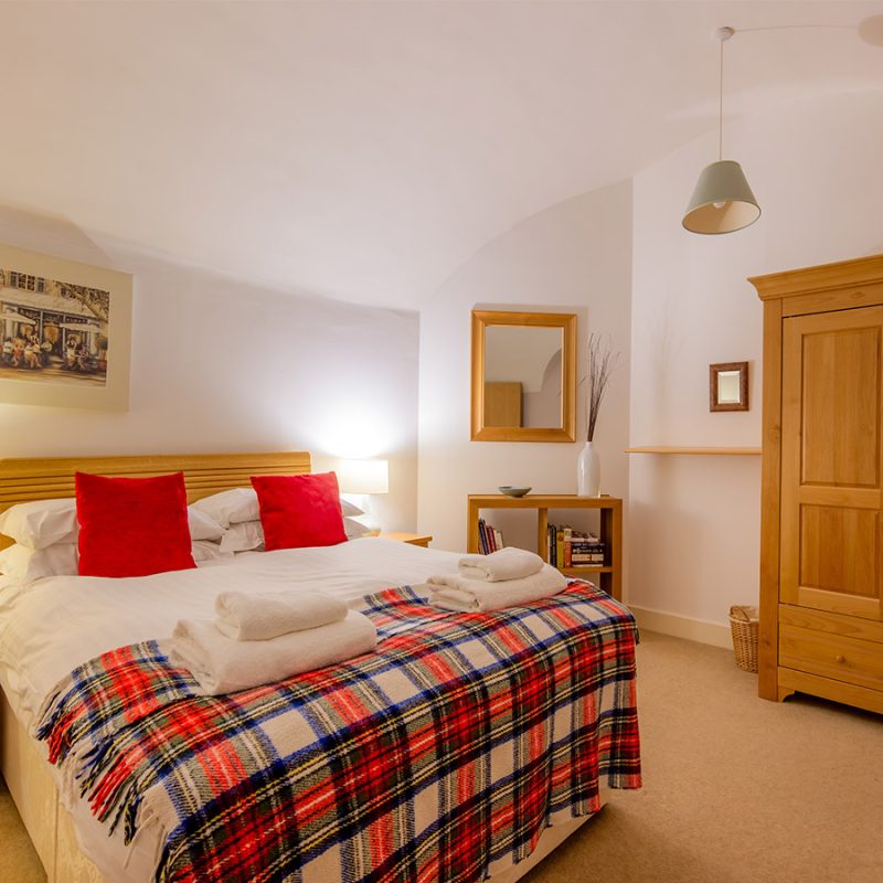 A cosy double bedroom lit up at night in the Major’s Apartment accommodation at Abbey Holidays in Loch Ness