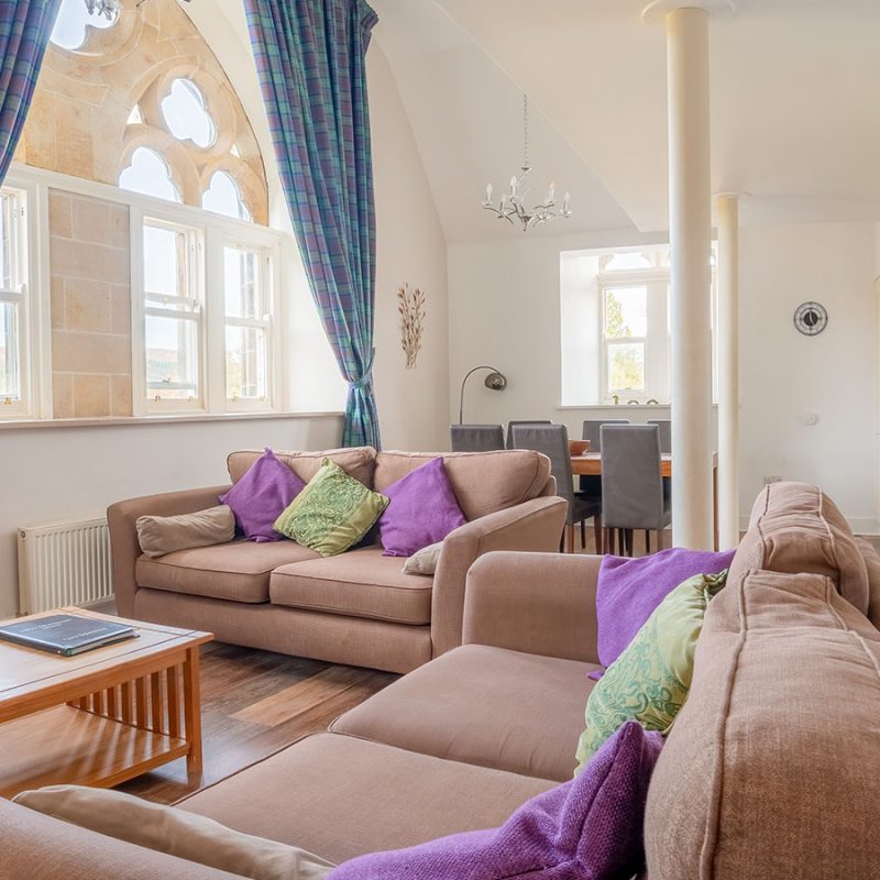 The open plan living area with beautiful historic arched church windows in The Caledonian accommodation at Abbey Holidays in Loch Ness