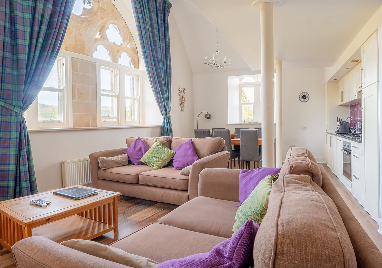 The open plan living area with beautiful historic arched church windows in The Caledonian accommodation at Abbey Holidays in Loch Ness