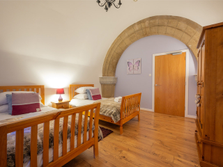 Abbey Church 25 - The Dunfermline accommodations twin bedroom with dramatic stone arch at Abbey Holidays by Loch Ness