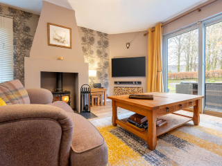 Strath Glass accommodation&#039;s living room with burning stove at Abbey Holidays Loch Ness
