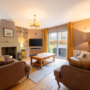 Strath Glass accommodation&#039;s living room with burning stove at Abbey Holidays Loch Ness