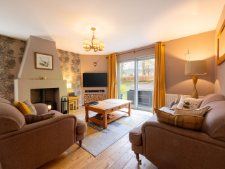 Strath Glass accommodation&#039;s living room with burning stove at Abbey Holidays Loch Ness