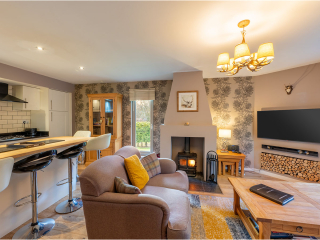 Strath Glass accommodation&#039;s open plan living with burning stove at Abbey Holidays Loch Ness
