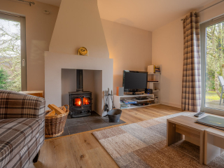 Courtyard Cottage 8 - Taigh Nan Caorach accommodation&#039;s living room with burning stove at Abbey Holidays Loch Ness