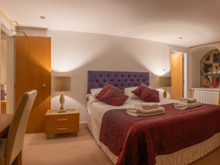 Moat House 5 The Ross accommodation&#039;s double bedroom with beautiful circular stained glass window at Abbey Holidays Loch Ness