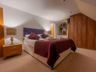 Moat House 5 The Ross accommodation&#039;s double bedroom with beautiful circular stained glass window at Abbey Holidays Loch Ness