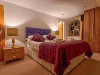 Moat House 5 The Ross accommodation&#039;s double bedroom with beautiful circular stained glass window at Abbey Holidays Loch Ness