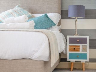 Monastery 10 - Brunel accommodation&#039;s double bed detail with quirky bedside table at Abbey Holidays Loch Ness