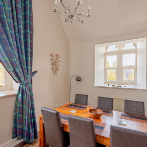 The Caledonian - Old School 12 accommodation&#039;s dining area with arched windows at Abbey Holidays Loch Ness