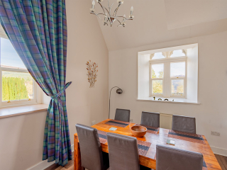 The Caledonian - Old School 12 accommodation&#039;s dining area with arched windows at Abbey Holidays Loch Ness