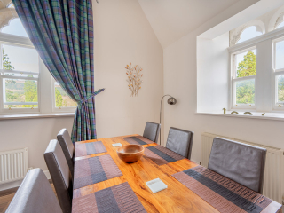 The Caledonian - Old School 12 accommodation&#039;s dining area with arched windows at Abbey Holidays Loch Ness
