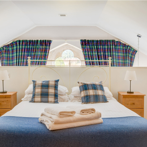 The Caledonian - Old School 12 accommodation&#039;s double bedroom on a mezzanine with spectacular arched ornate windows at Abbey Holidays Loch Ness