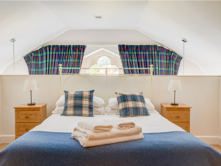 The Caledonian - Old School 12 accommodation&#039;s double bedroom on a mezzanine with spectacular arched ornate windows at Abbey Holidays Loch Ness
