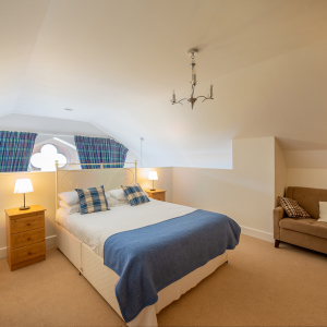 The Caledonian - Old School 12 accommodation&#039;s double bedroom on a mezzanine with spectacular arched ornate windows at Abbey Holidays Loch Ness