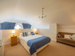 The Caledonian - Old School 12 accommodation&#039;s double bedroom on a mezzanine with spectacular arched ornate windows at Abbey Holidays Loch Ness