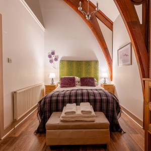 The Caledonian - Old School 12 accommodation&#039;s double bedroom with stunning arched beams at Abbey Holidays Loch Ness