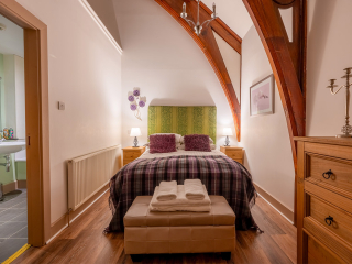 The Caledonian - Old School 12 accommodation&#039;s double bedroom with stunning arched beams at Abbey Holidays Loch Ness