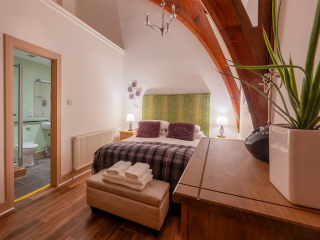 The Caledonian - Old School 12 accommodation&#039;s double bedroom with stunning arched beams and en-suite at Abbey Holidays Loch Ness