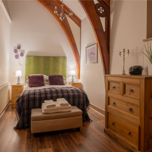 The Caledonian - Old School 12 accommodation&#039;s double bedroom with stunning arched beams at Abbey Holidays Loch Ness