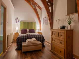 The Caledonian - Old School 12 accommodation&#039;s double bedroom with stunning arched beams at Abbey Holidays Loch Ness