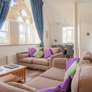 The Caledonian - Old School 12 accommodation&#039;s open plan living area with stunning arched, ornate and decorative windows at Abbey Holidays Loch Ness